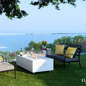 Outdoor patio setup with fire pit table, chairs, and a scenic view.