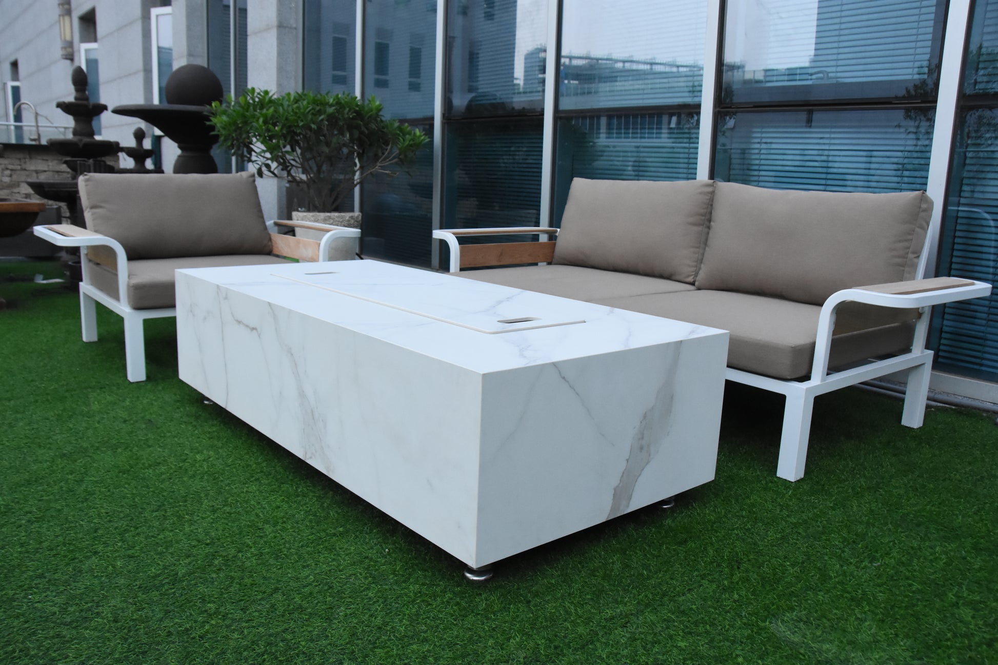 Outdoor furniture set with a marble-textured fire table cover on a grassy area.